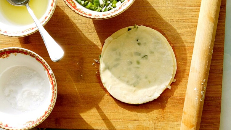 香脆饺子皮葱油饼,用擀面杖反复几次擀成圆形的饼，一个饺子皮葱油饼就完成了，放在干燥的盘子里