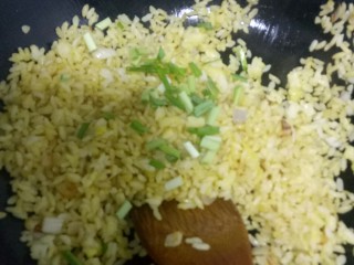 黄金炒米,根据个人口味放入适量盐，搅拌均匀，撒上蒜苗碎，关火。