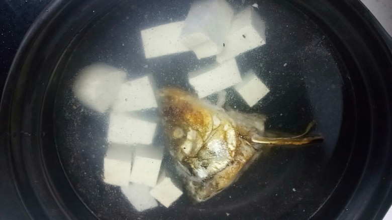 鱼头炖豆腐
,砂锅中放入适量水，放入鱼头、豆腐块，如果家里没有砂锅，可以在刚才煎鱼的铁锅里直接加水炖。