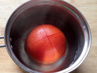 百变鸡蛋+番茄鸡蛋饼,先将番茄用刀划十字，放入开水中烫一下。