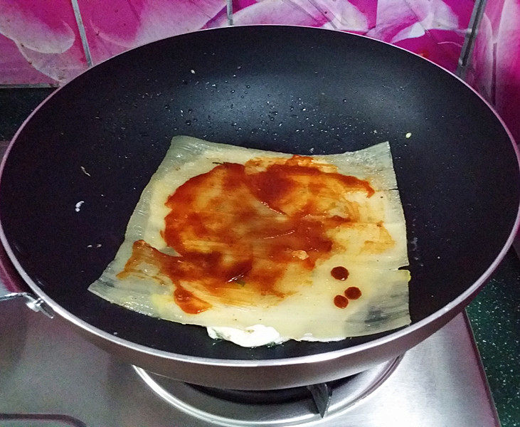 烤冷面,待蛋液快要凝固时及时翻面、抹上番茄酱和冷面酱