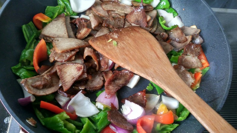 回锅牛肉,青椒快要熟的时候将牛肉，洋葱倒入锅中翻炒。