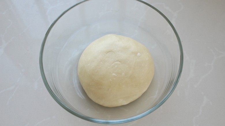 原味面包甜甜圈,将面团整理好放入容器中，覆盖保鲜膜放到温暖处进行发酵