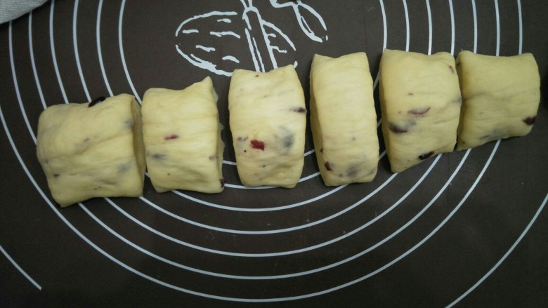 蔓越莓面包圈,将两份面团分别揉成长筒型，切成大约相等的小面团。盖布静置五分钟。
