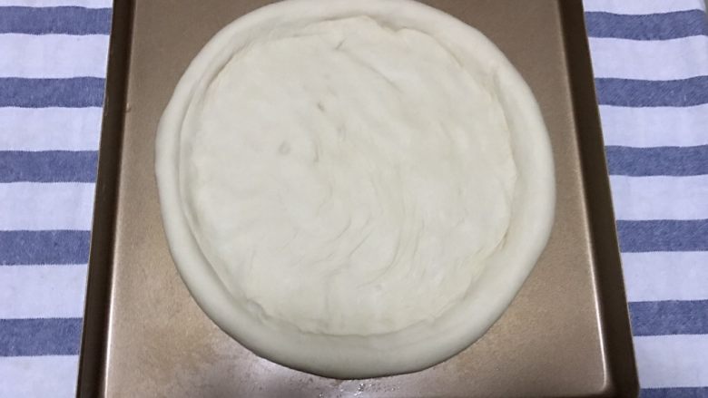 火腿虾仁披萨,然后把面饼卷在擀面杖上帮助挪到烤盘里，用手把中间部分压平整形，放在一旁静置10-20分钟，等待二次发酵