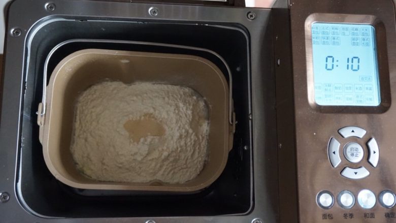 黑豆红枣豆浆小餐包,在面粉顶端加入酵母，将面包桶放入到东菱1352AE-3C面包机里，选择和面10分钟