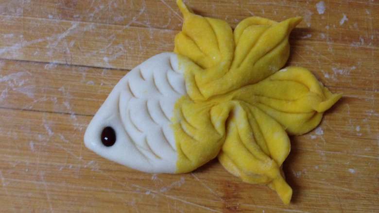 金鱼馒头,用勺沿压或是吸管出花纹，
最后在顶部按上一颗红豆做眼睛，放入温暖湿润处发酵至两倍大
