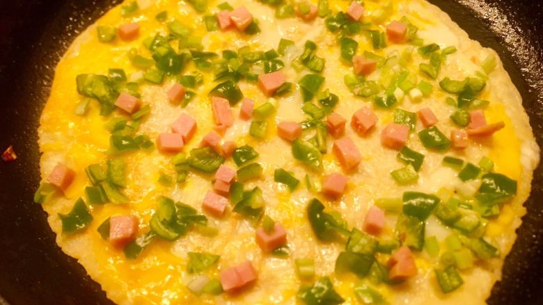 辣椒香葱午餐肉鸡蛋卷饼,小火慢慢煎至表面微黄，全部食材都会沾在蛋液上了。