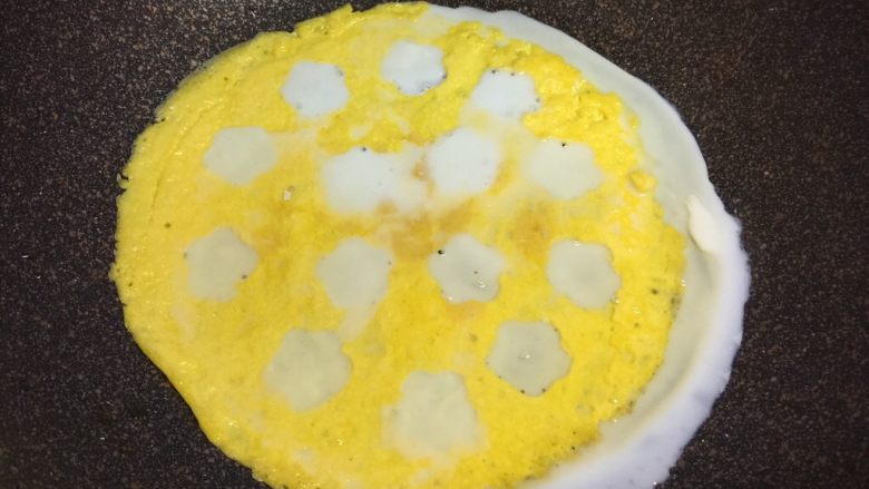 百变鸡蛋+小花茄汁蛋包饭,蛋黄蛋皮铺回不粘锅里，把蛋清用小勺填满小花空里，煎熟。我把蛋清全倒进去了，锅没有放平，歪了一边，不过不影响，一会儿边还要装饰，可以盖住白边。