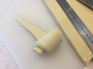 可颂,将面团擀至厚度0.5的长方形，并借助长尺切割成等腰三角形，从底向顶点卷起。注意覆盖重叠部分不能有干粉，最好用刷子沾水湿润。