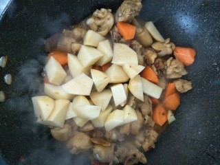 土豆烧鸡块,鸡块炒至变色倒入胡萝卜土豆翻炒