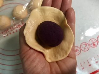 黄金紫薯饼,把胡萝卜面团按扁，擀成中间厚四周薄的圆皮，把紫薯馅放在中间。