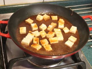 豆腐肉丸子麻婆煮,酱汁煮滚后，将剩下一半的板豆腐切块后放入豆瓣酱汁中，煮1-2分钟，让豆腐入味。