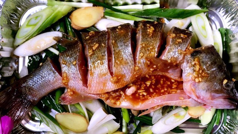 锡纸焗白贝鲈鱼,锡纸盘底部放葱姜 鱼铺在上面淋上腌制鱼的汤汁 再淋上少许油