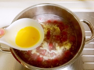 酒酿桂花粉红鸡蛋丸子,然后快速打入鸡蛋液，开小火将鸡蛋液画圈圈淋入锅内，此时不能翻动锅内，以免影响蛋液的形成。