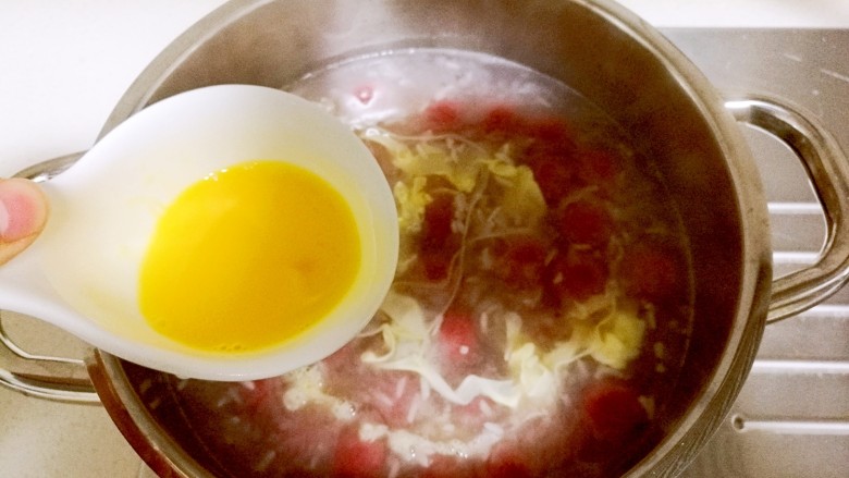 酒酿桂花粉红鸡蛋丸子,然后快速打入鸡蛋液，开小火将鸡蛋液画圈圈淋入锅内，此时不能翻动锅内，以免影响蛋液的形成。