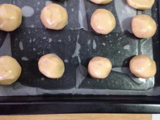 花生酱版花生小饼干,搓成球，排在铺了油纸的烤盘上，中间要有间距。