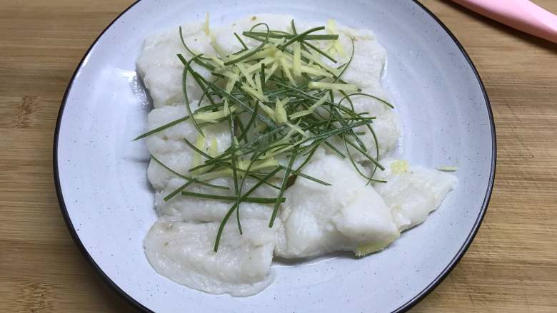 清蒸龙利鱼 ,8分钟后把蒸好的龙利鱼取出，倒去水后放上葱、姜丝。