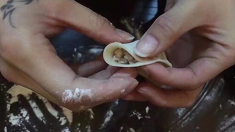 香菇猪肉饺,饺子皮平放手板心，右手食指和拇指在中心线捏一下，捏紧。。