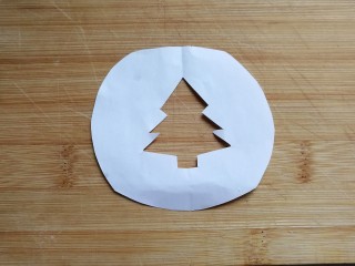 圣诞树纸杯蛋糕,然后找张小纸片画上圣诞树轮廓，并用剪刀在中间剪去多余部分，便得到漏空圣诞树小图形；