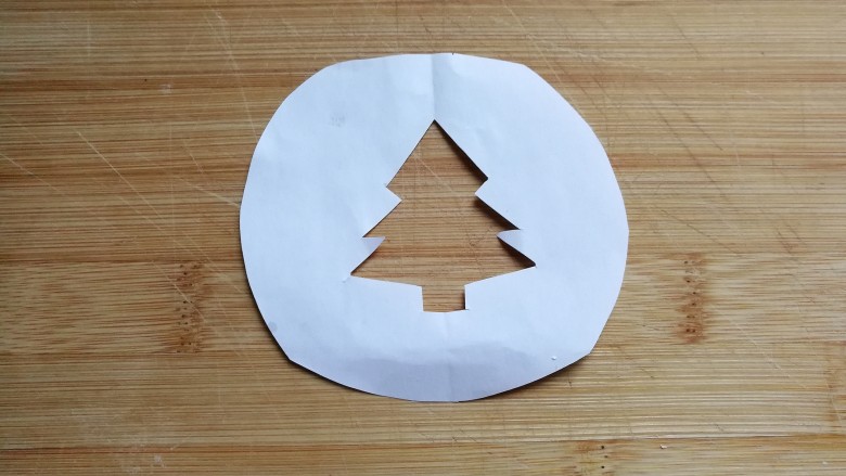 圣诞树纸杯蛋糕,然后找张小纸片画上圣诞树轮廓，并用剪刀在中间剪去多余部分，便得到漏空圣诞树小图形；