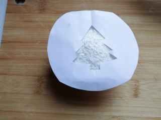 圣诞树纸杯蛋糕,将漏空纸放在撒好的蛋糕椰蓉表面上；