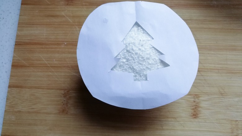 圣诞树纸杯蛋糕,将漏空纸放在撒好的蛋糕椰蓉表面上；