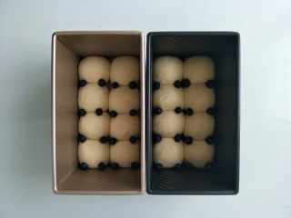 熊猫小面包,面团放在温暖湿润处进行二次发酵，发酵两倍大，用筷子将黑色面团放在耳朵的位置，盖上土司盒