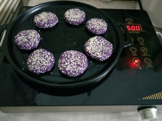 紫薯芝麻饼,烤盘薄薄的刷一层油，放入紫薯饼小火煎熟，也可以用平底锅或者放入烤箱烤
