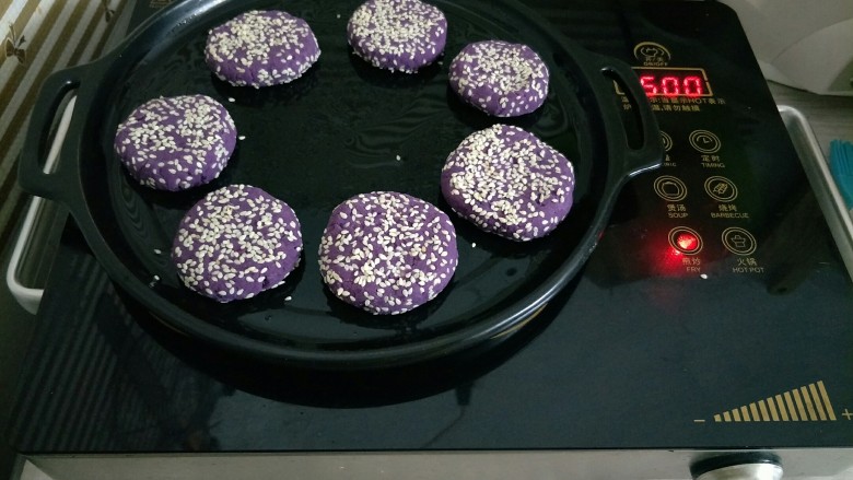 紫薯芝麻饼,烤盘薄薄的刷一层油，放入紫薯饼小火煎熟，也可以用平底锅或者放入烤箱烤