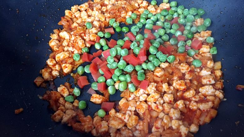 炒饭秀+辣白菜炒饭,倒入煮熟的胡萝卜和豌豆翻炒均匀。
