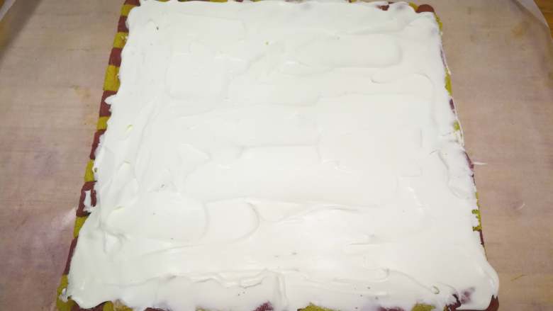 浓浓圣诞气息的—蛋糕卷,底部重新铺一张油纸，蛋糕尾部切一斜边。奶油加糖打8分发，辅到蛋糕上面，尾部涂薄一点。