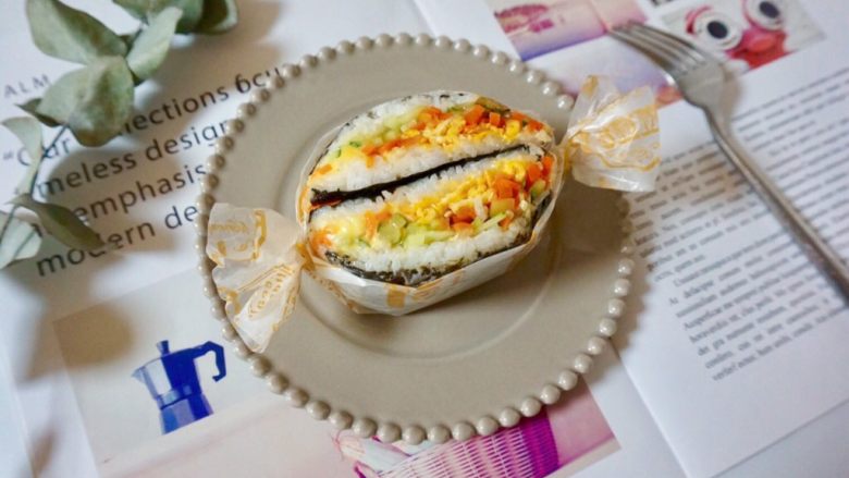 米饭三明治,把米饭三明治从中间对半切开，包上硅油纸。