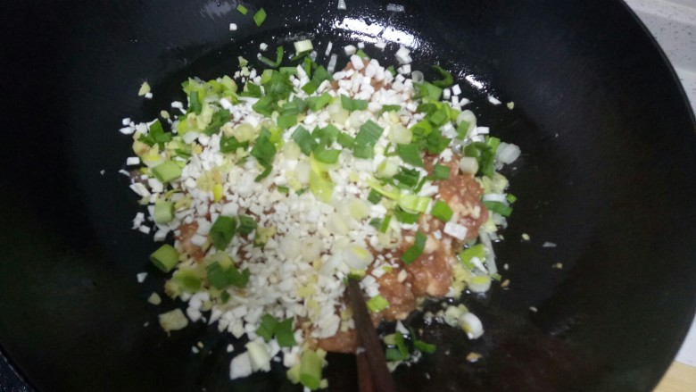 翡翠猪肉韭菜饺子,将猪肉放入锅中加入杏鲍菇、另一半的葱、姜、蒜苗末。