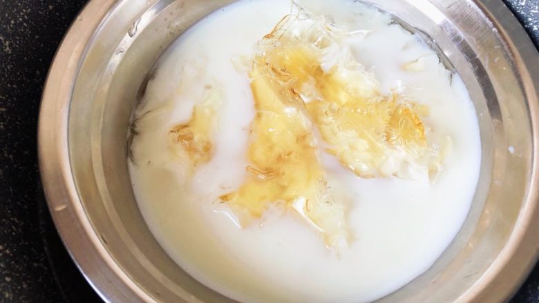 镜面百香果慕斯蛋糕,泡软后放入180g牛奶的牛奶里，隔热水加热至吉利丁片完全融化。