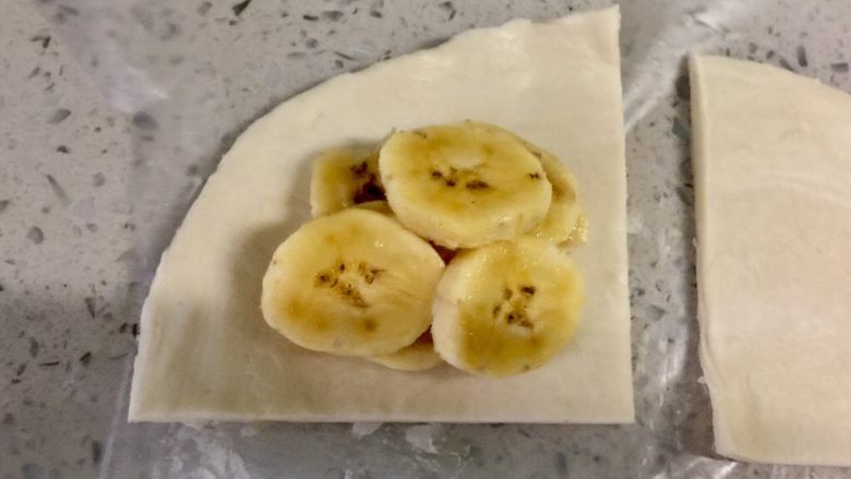 快手飞饼香蕉派,把米蕉片放在其中一片飞饼皮上。