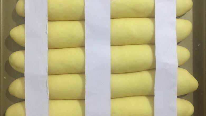 奶香红薯排包,用一张A4指裁剪成3条这样的长条放表面准备筛高粉