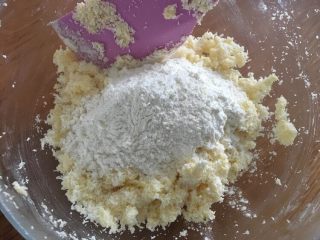 椰蓉小酥球,继续加入过筛的低筋面粉，还是用压的方式，让面粉充分混合到椰蓉黄油霜里；