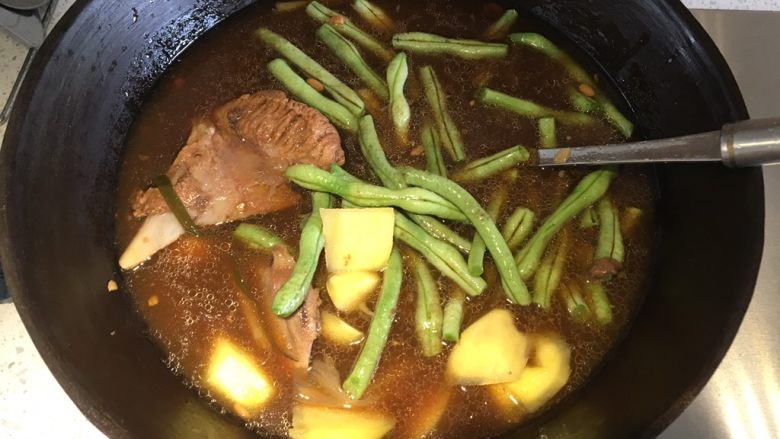 东北·乱炖,用大铁锅盛出骨头汤和一块带肉比较多的骨头，煮开，加入豆角和土豆，盖上盖子先炖熟豆角和土豆
