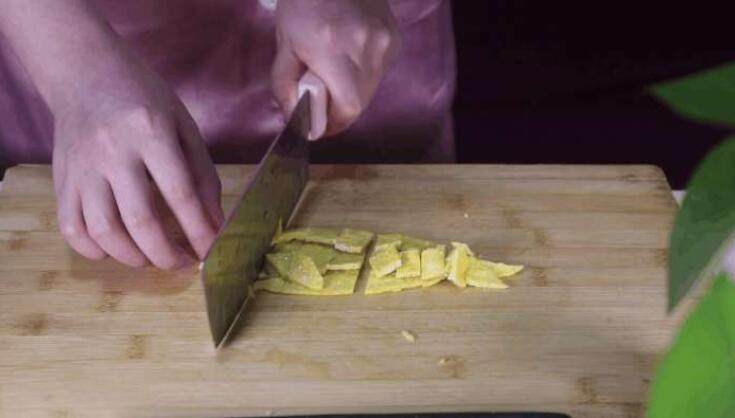 蛋包饭的创新吃法，上桌大家都不忍心动筷子,将煎好的蛋皮出锅放在案板上，用刀子在蛋皮上切成长条状备用。