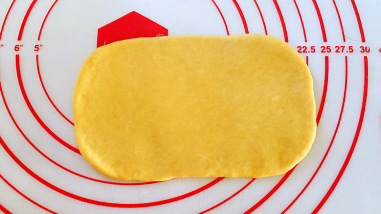 南瓜麻薯红豆面包,取1个面团，收口朝下，用手拍扁排气后，擀成椭圆形。