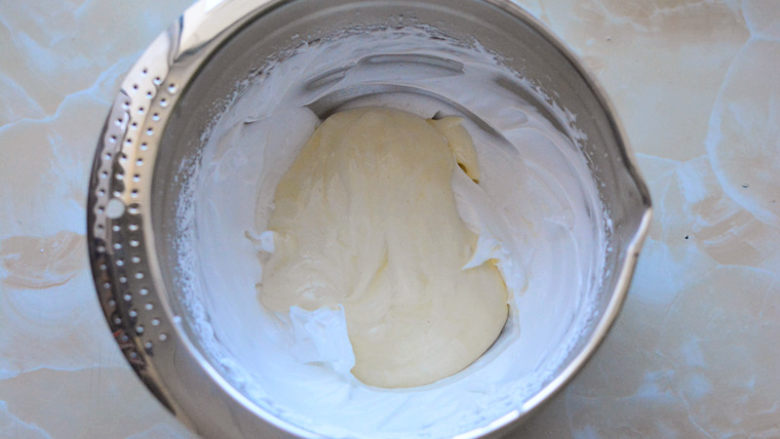 酸奶戚风蛋糕,然后将混合好的面糊全部倒入剩余的蛋白霜里，翻拌均匀。拌好的面糊细腻有光泽。
