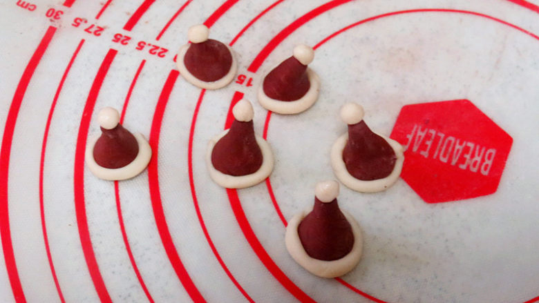 圣诞季【圣诞小鸡家族馒头】,红色面团分出来6个3g的小面团，用手捏成圣诞帽子的形状，再把白色面团搓长，做成围边