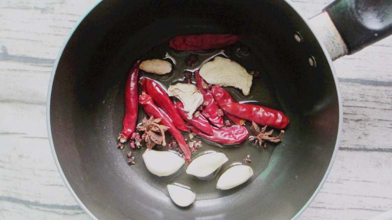 钵钵鸡,接着我们再来炒个底料，炒锅倒油烧热，放入红辣椒，香叶，花椒，葱段，蒜瓣和姜片，炒出香味。