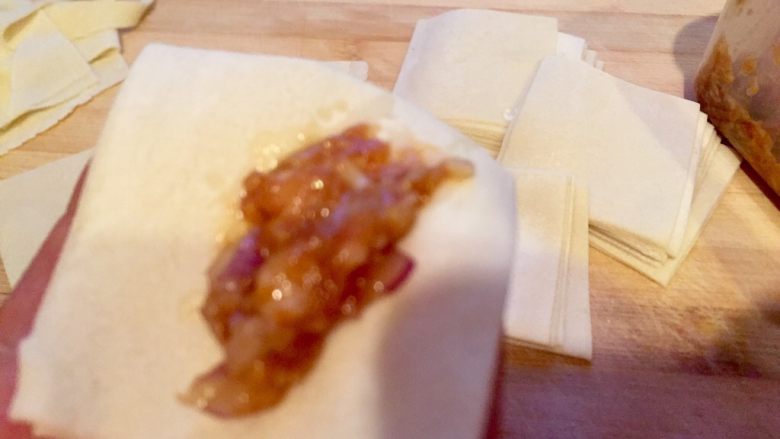 乡味～重庆小吃红油抄手,手拿一张面皮放入肉馅。