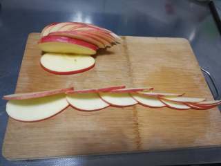 天鹅苹果、花式苹果（2种花式切苹果方法）,取一块切下来的苹果块，从中间位置左右切斜刀，切出图中形状。（切不了这么薄也没关系，只要能切出3层效果就有了），同样的方法切好3块苹果块。