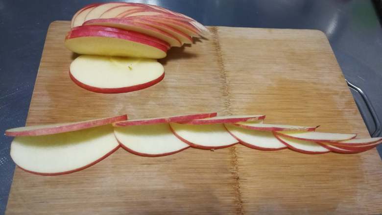 天鹅苹果、花式苹果（2种花式切苹果方法）,取一块切下来的苹果块，从中间位置左右切斜刀，切出图中形状。（切不了这么薄也没关系，只要能切出3层效果就有了），同样的方法切好3块苹果块。