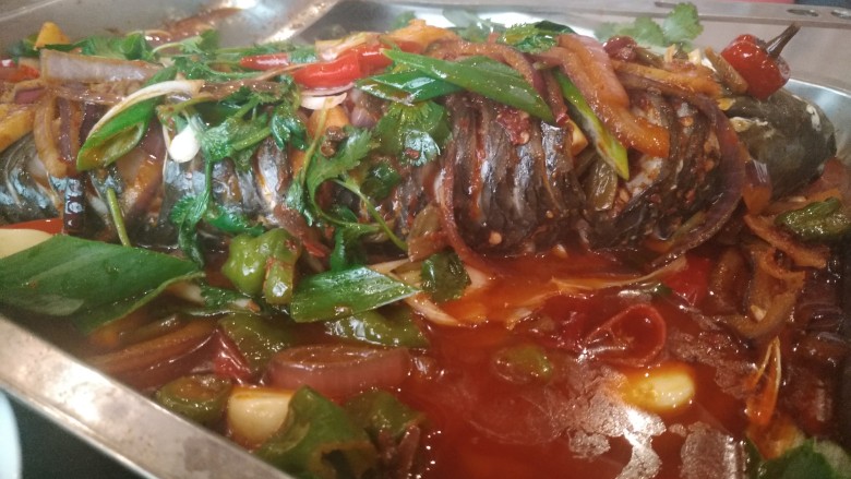 家庭版孜然烤鱼,这个时候鱼也差不多蒸好了，把刚刚做好的配菜均匀的淋在鱼上面，撒点香菜，大葱。