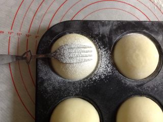 奶黄小餐包,在面包表面上放一个叉子，筛上高筋面粉。