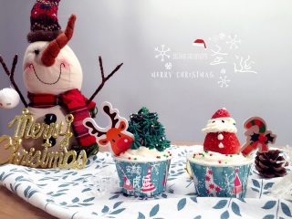 圣诞纸杯蛋糕,将三分之二打发好的淡奶油装入裱花袋中（圆形裱花嘴）在蛋糕上挤一层铺满顶部，草莓上挤出圣诞老人的头、胡子，再把草莓顶部放上去做帽子，挤一点在尖端装饰帽子，再用芝麻当眼睛。剩下的三分之一淡奶油中加入绿色色素打发均匀装入裱花袋中（8爪菊花嘴），先挤一层白奶油在纸杯蛋糕上，在中间放一颗草莓，然后沿着草莓外面挤出绿色奶油装裱成圣诞树，撒适量糖珠装饰插上卡片即可。